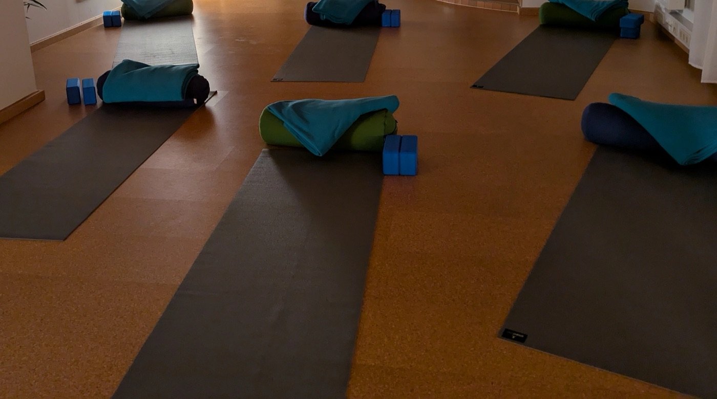 Matten mit Decken, Bolstern und blauen Yogablöcken auf dem warmen Korkboden